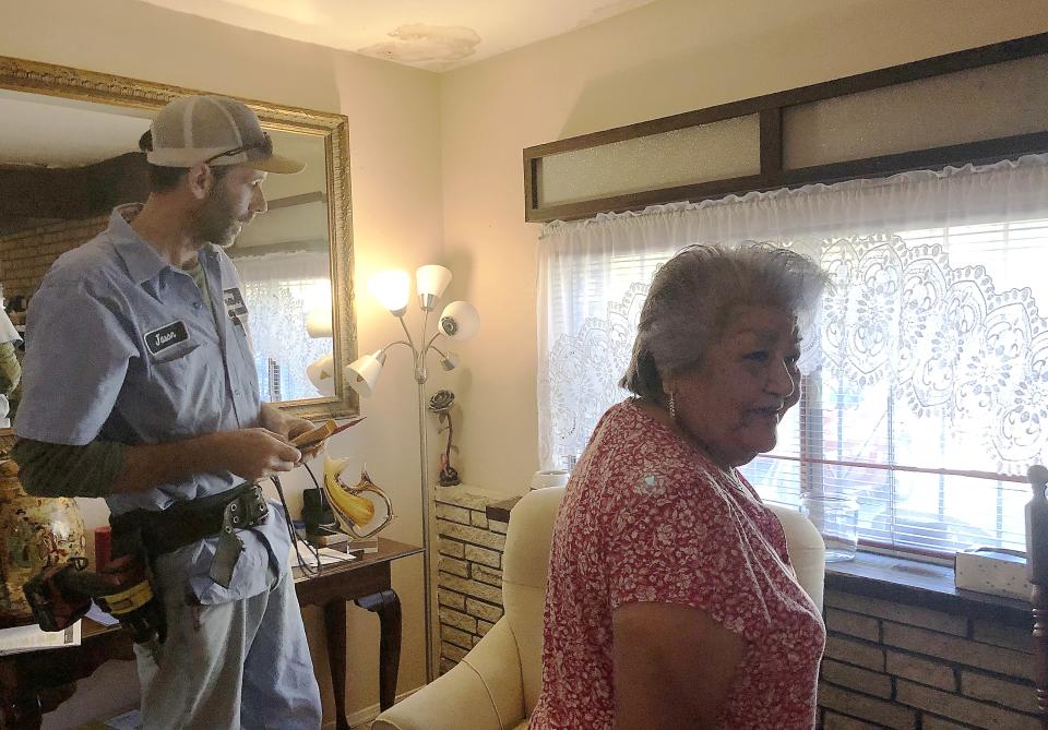 Lighting Inc. electrician Jason Chedester meets with homeowner Olivia R. Hernandez last month. The company is donating electrical services for the family, whose home needs major repairs.