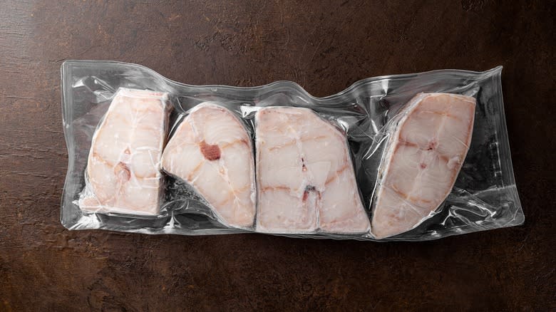 frozen vacuum-sealed catfish steaks on wooden surface