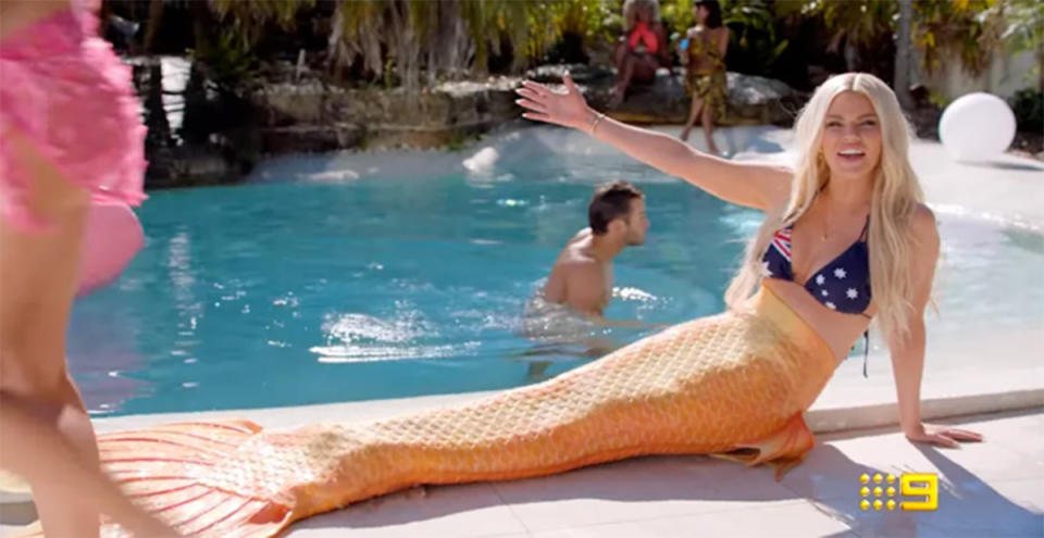 Sophie Monk wears an Australian flag bikini top and a mermaid tail alongside a swimming pool in the Love Island 2021 promo. Photo: Channel Nine.