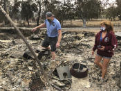 Kevin Conant and his wife, Nikki, walk through debris of their burnt home and business "Conants Wine Barrel Creations," after the Glass/Shady fire completely engulfed it, Wednesday, Sept. 30, 2020, in Santa Rosa, Calif. The Conants escaped with their lives, which we are grateful for, but they barely made it out with the clothes on their backs in the wake of the fire. The Glass and Zogg fires are among nearly 30 wildfires burning in California. (AP Photo/Haven Daley)