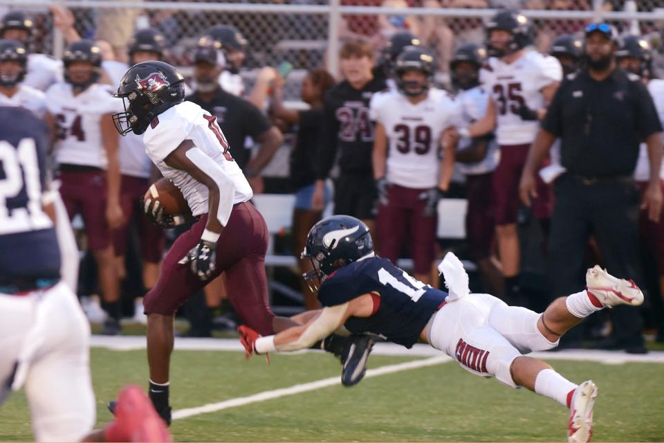 Fort Walton Beach's Sean Rusinshak reaches to tackle Navarre's Eddie Love Jr during Friday night's home game against Navarre High School.