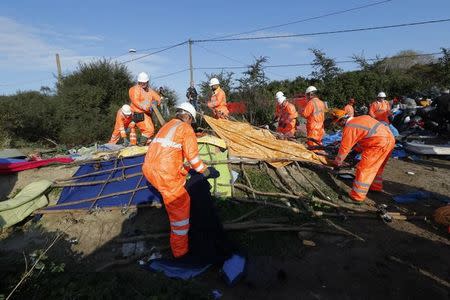 Workmen tear down a makeshift shelter on the second day the evacuation of migrants and their transfer to reception centers in France, as part of the dismantlement of the camp called the "Jungle" in Calais, France, October 25, 2016. REUTERS/Philippe Wojazer