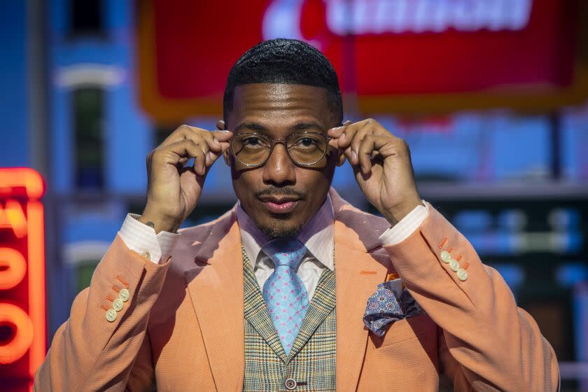 A man wearing an orange suit putting on his eyeglasses