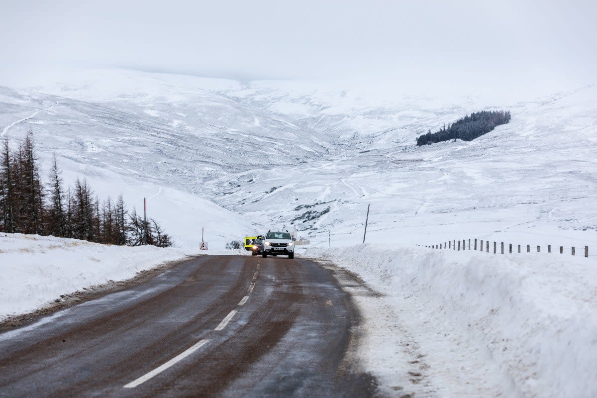 Cars make their way along the A939 after heavy snowfall in the Scottish Highlands (PA)