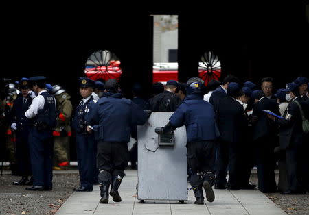 Members of a police bomb disposal squad move a blast protection device to the site of an explosion at the Yasukuni shrine in Tokyo, Japan, November 23, 2015. REUTERS/Toru Hanai