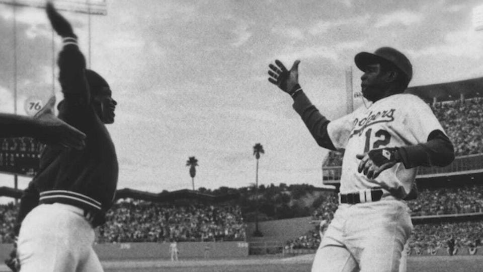 Glenn Burke, left, goes to greet teammate Dusty Baker after Baker hit a home run in 1977.