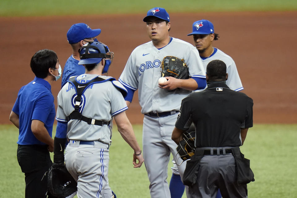 Toronto Blue Jays starting pitcher Hyun Jin Ryu, center, holding ball, reacts after getting hurt during the fourth inning of a baseball game against the Tampa Bay Rays Sunday, April 25, 2021, in St. Petersburg, Fla. Ryu left the game. (AP Photo/Chris O'Meara)