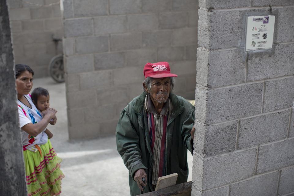 In this Feb. 11, 2014 photo, Santiago Vazquez, 95, stands at the entrance of his son's home that is under construction with state assistance in Cochoapa El Grande, Mexico. In the 400 poorest and most malnourished of the country’s 2,400 municipalities that include Cochoapa, the administration of Enrique Pena Nieto has been trying to enroll more people in existing social programs such as Opportunities, which provides a small monthly stipend to qualifying poor Mexicans. (AP Photo/Dario Lopez-Mills)