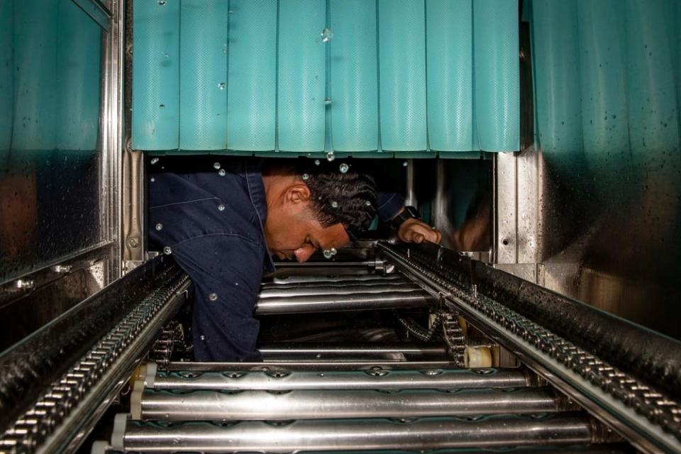 A photo of a man with half his arm in a piece of machinery.