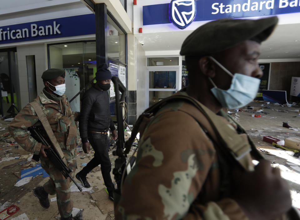 Soldiers escort a man suspected of looting from inside a trashed shopping mall in Soweto, near Johannesburg, Tuesday July 13, 2021. South Africa's rioting continued Tuesday as police and the military tried to halt the unrest in poor areas of two provinces, in Gauteng and KwaZulu-Natal, that began last week after the imprisonment of former President Jacob Zuma. (AP Photo/Themba Hadebe)