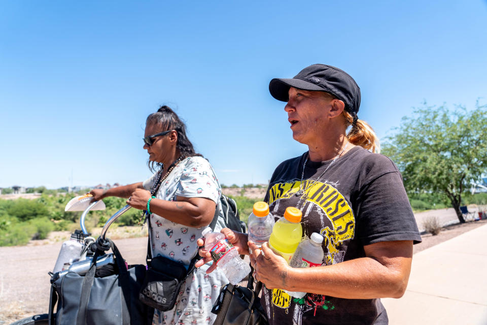 Lupe Perez (left), 46, and Christal Barnes, 47, walk along the Rio Salado riverbed where they live in Tempe on Aug. 31, 2022. Tempe gave notice for people living in the river bottom to vacate by Aug. 31.
