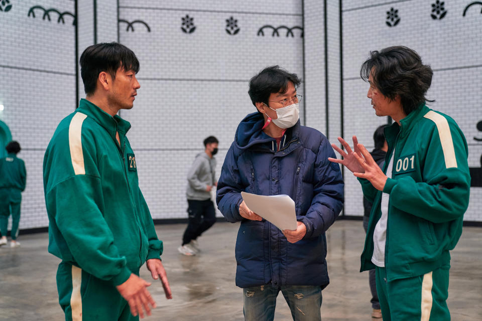 Lee Jung-jae, right, talks with Squid Game creator Hwang Dong-hyuk, center. (Noh Juhan / Netflix)