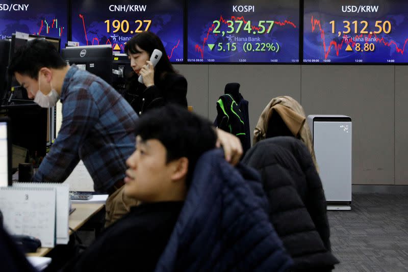 FILE PHOTO: Currency dealers work in front of an electronic board showing the Korean Composite Stock Price Index (KOSPI) at a dealing room of a bank, in Seoul