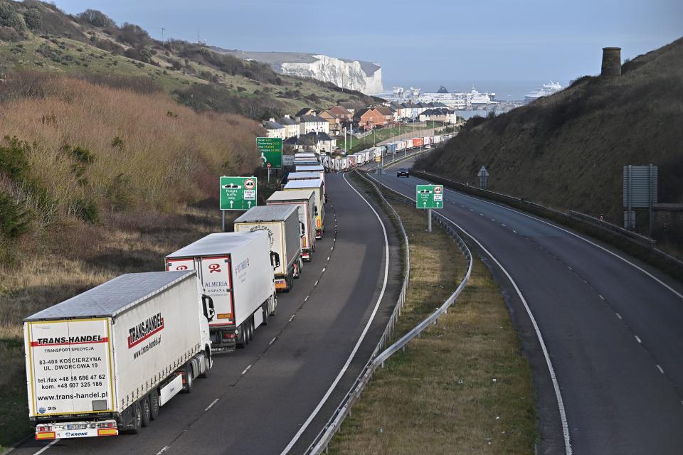 The Dover Traffic Access Protocol (TAP) scheme on the A20 is seen in action as freight lorries queue on the main route into the port of Dover on the south coast of England on December 18, 2020 with the White Cliffs and a ferry in the background. - Questions were asked in the House of Lords on December 17 on the government's state of preparedness for Brexit. UK importers are suffering from delays at Felixstowe and Southampton and there are fears of major delays at Dover from the new year. (Photo by Ben STANSALL / AFP) / The erroneous mention[s] appearing in the metadata of this photo by Ben STANSALL has been modified in AFP systems in the following manner: Picture taken on [December 18, 2020] instead of [December 17, 2020]. Please immediately remove the erroneous mention[s] from all your online services and delete it (them) from your servers. If you have been authorized by AFP to distribute it (them) to third parties, please ensure that the same actions are carried out by them. Failure to promptly comply with these instructions will entail liability on your part for any continued or post notification usage. Therefore we thank you very much for all your attention and prompt action. We are sorry for the inconvenience this notification may cause and remain at your disposal for any further information you may require. (Photo by BEN STANSALL/AFP via Getty Images)
