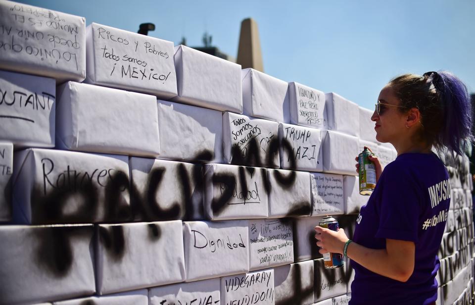 An activist writes the word 'Racism' on a mock wall during an anti-Trump march in Mexico City, on February 12, 2017. Mexicans took to the streets against US President Donald Trump, hitting back at his anti-Mexican rhetoric and vows to make the country pay for his 'big, beautiful' border wall. / AFP / RONALDO SCHEMIDT        (Photo credit should read RONALDO SCHEMIDT/AFP/Getty Images)