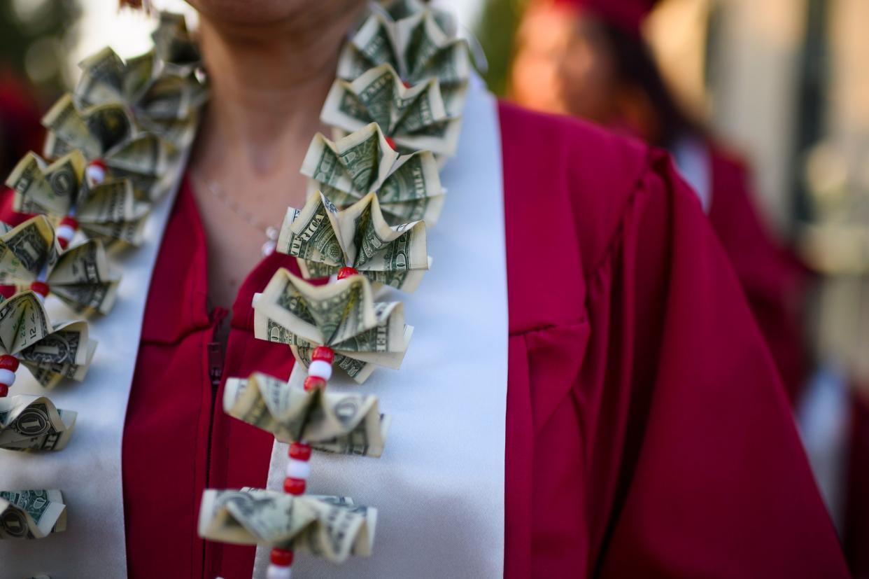 A graduating student wears a money lei, a necklace made of US dollar bills, at the Pasadena City College graduation ceremony, June 14, 2019, in Pasadena, California. - With 45 million borrowers owing $1.5 trillion, the student debt crisis in the United States has exploded in recent years and has become a key electoral issue in the run-up to the 2020 presidential elections.
