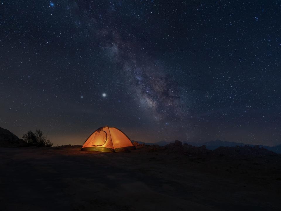 An illuminated tent is set against a dark night sky.
