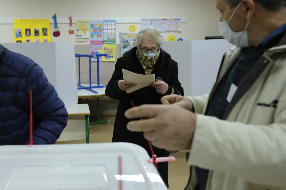 A woman prepares her ballot for the local elections at a polling station in Mostar, Bosnia, Sunday, Dec. 20, 2020. Divided between Muslim Bosniaks and Catholic Croats, who fought fiercely for control over the city during the 1990s conflict, Mostar has not held a local poll since 2008, when Bosnia's constitutional court declared its election rules to be discriminatory and ordered that they be changed. (AP Photo/Kemal Softic)