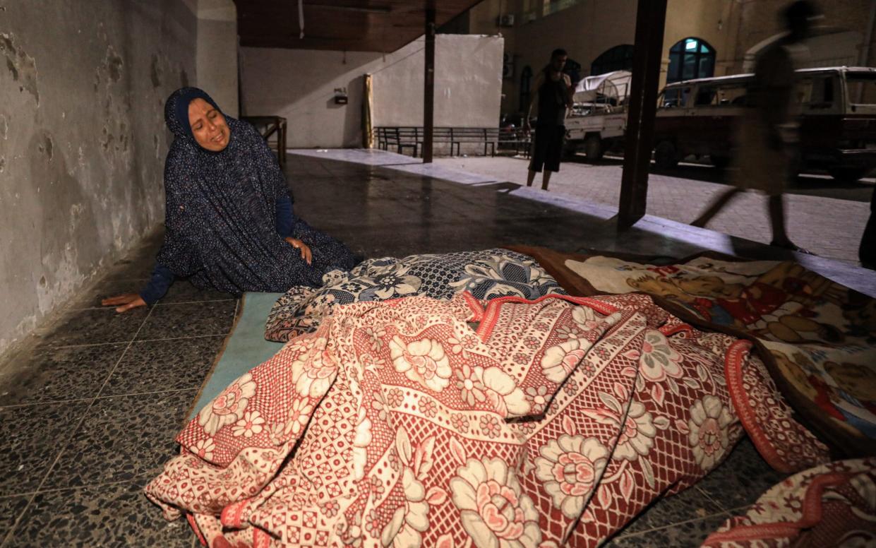 A Palestinian woman mourns next to the dead bodies at Al-Ahli Baptist Hospital