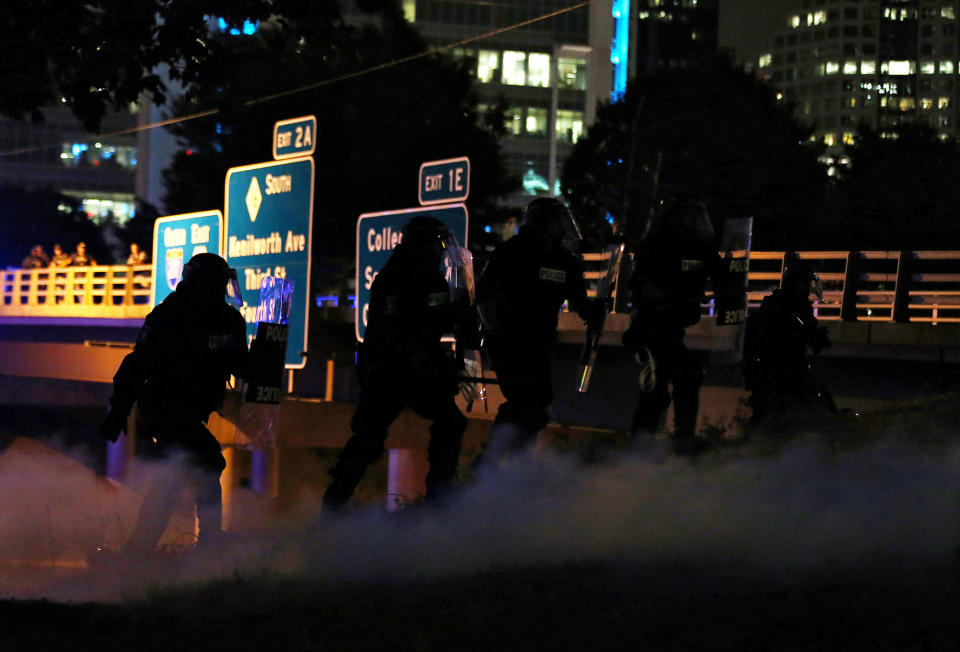 Police in riot gear follow a wave of tear gas as they chase demonstrators off the highway