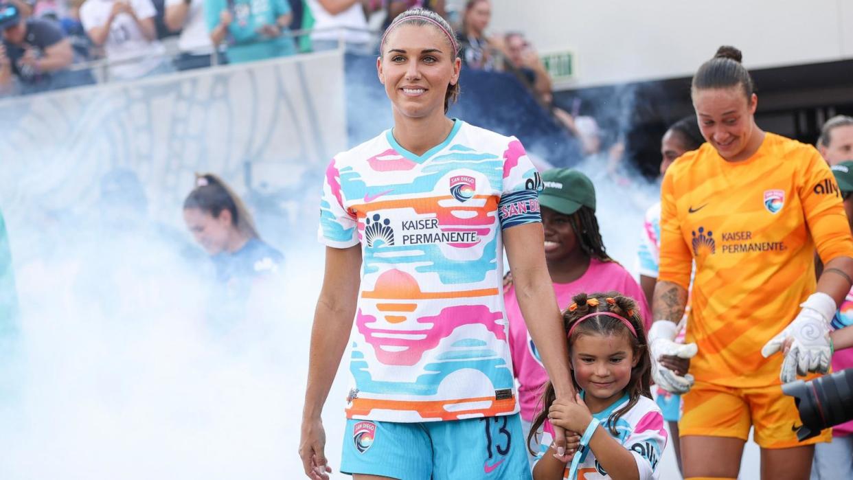 PHOTO: Alex Morgan of San Diego Wave FC walks onto the pitch with her daughter, Charlie before playing the last match of her career Sept. 8, 2024, in San Diego. (Meg Oliphant/Getty Images)