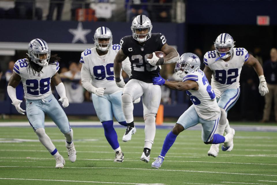 Las Vegas Raiders running back Josh Jacobs (28) runs the ball for a first down as Dallas Cowboys' Malik Hooker (28), Justin Hamilton (99), Jourdan Lewis (26) and Dorance Armstrong (92) attempt to make the stop in overtime of an NFL football game in Arlington, Texas, Thursday, Nov. 25, 2021. (AP Photo/Michael Ainsworth)