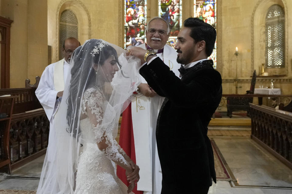 Pakistani Christian groom Sharoon Arjumand John raises his bride's veil during their wedding ceremony at Holy Trinity Cathedral in Karachi, Pakistan, Saturday, Jan. 27, 2024. Pakistan's winter months are all about weddings. The cooler temperatures between November and February see millions of people attending festivities every week. The wedding season has become a calendar fixture, like birthdays. It even has a nickname, Decemberistan. (AP Photo/Fareed Khan)