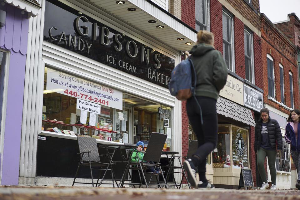 FILE - In this Nov. 22, 2017 file photo, pedestrians pass the storefront of Gibson's Food Mart & Bakery in Oberlin, Ohio. A jury has awarded $11 million to a father and son who claimed Ohio's Oberlin College and an administrator hurt their business and libeled them during a dispute that triggered protests and allegations of racism following a shoplifting incident. (AP Photo/Dake Kang, File)