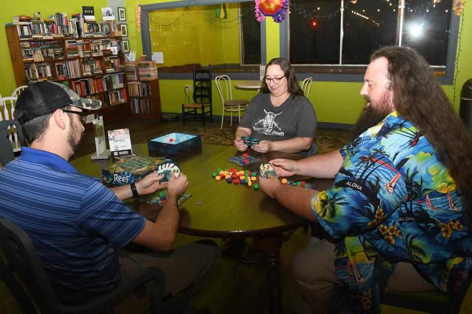 Fighting Hand Brewing Company owner Tiffany Lindsey (center) plays "Reef" with Central Louisiana Gamer’s Guild members Louis Busby (far left) and Matt Gaspard. The group plans to meet at Fighting Hand one Wednesday a month to play hobby board games.