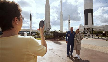 Retired astronaut Jon McBride (back L) poses for a photo with a visitor taking part in a tour at the 'Rocket Garden' of the Kennedy Space Center in Cape Canaveral, Florida October 2, 2013. REUTERS/Michael Brown