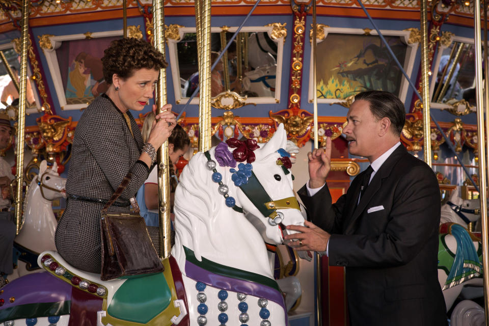 A woman rides a carousel horse while a man stands beside her