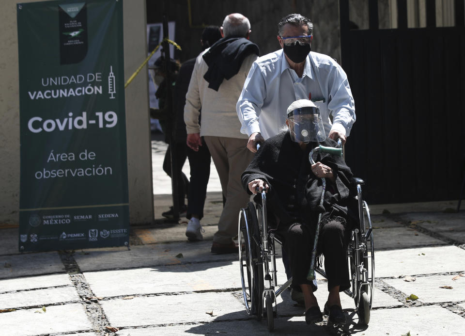 A wheelchair-bound elderly person who got a shot of the AstraZeneca vaccine against COVID-19 is pushed to an observation area, at a vaccination center set up in the Magdalena Contreras area of Mexico City, Monday, Feb. 15, 2021, as Mexico starts vaccinating people over age 60 against the new coronavirus. (AP Photo/Marco Ugarte)