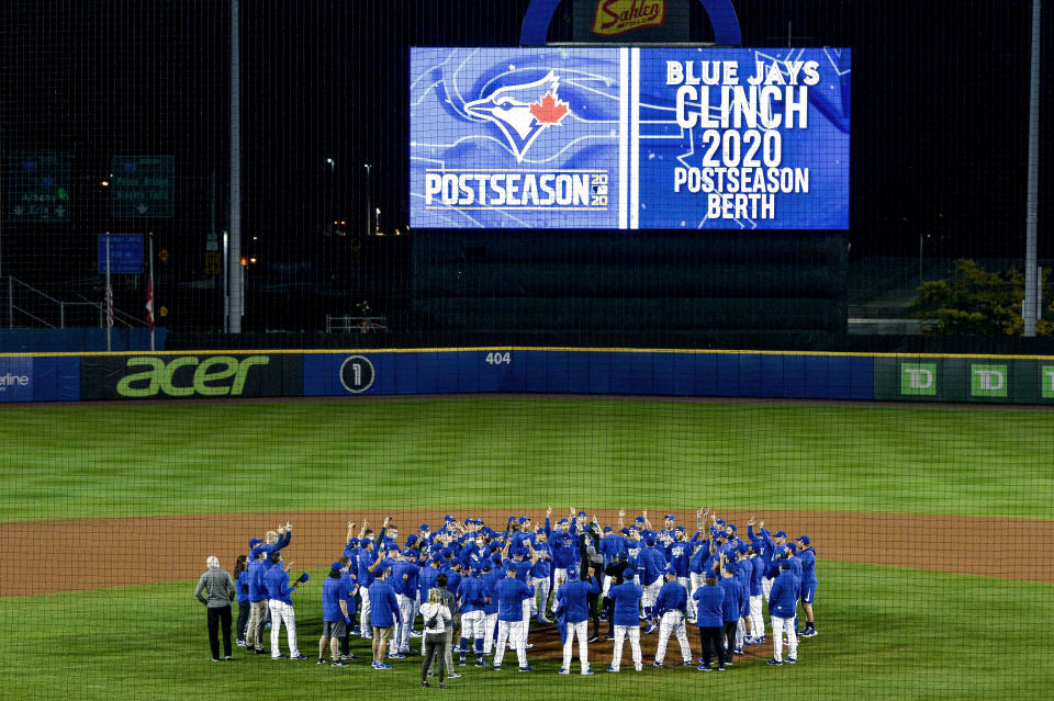 Toronto Blue Jays players, coaches and staff celebrate a 4-1 win over the New York Yankees in a baseball game in Buffalo, N.Y., Thursday, Sept. 24, 2020. Toronto clinched a postseason berth with the win. (AP Photo/Adrian Kraus)