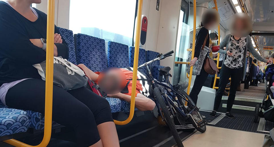 Cyclist laying down on Onehunga train towards Auckland, stopping woman with baby from sitting.