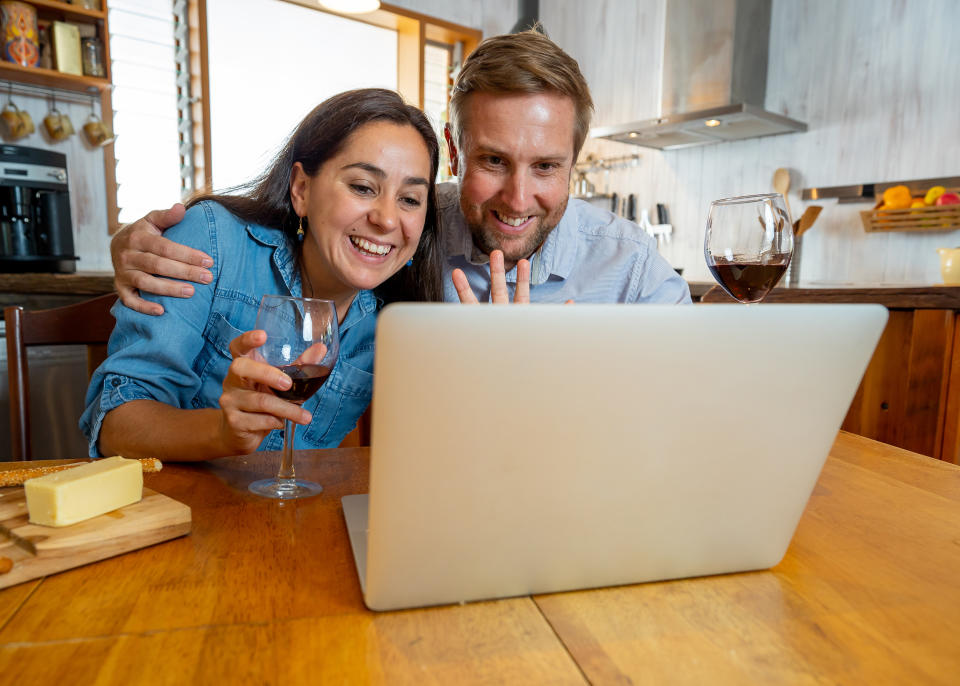 COVID-19 Stay safe Stay connected. Happy young couple video calling friends using laptop at home. Man and woman online chatting with family during coronavirus lockdown and social distancing. (Getty Images)