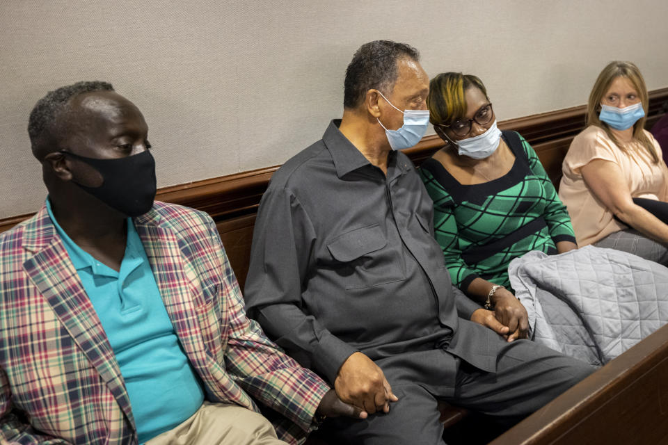 The Rev. Jesse Jackson, center, holds hands with Marcus Arbery, center, father of Ahmaud Arbery, left, Ahmaud Arbery's mother, Wanda Cooper-Jones, right, during the trial of Greg McMichael and his son, Travis McMichael, and a neighbor, William "Roddie" Bryan in the Glynn County Courthouse, Monday, Nov. 15, 2021, in Brunswick, Ga. The three are charged with the February 2020 slaying of 25-year-old Ahmaud Arbery. (AP Photo/Stephen B. Morton, Pool)