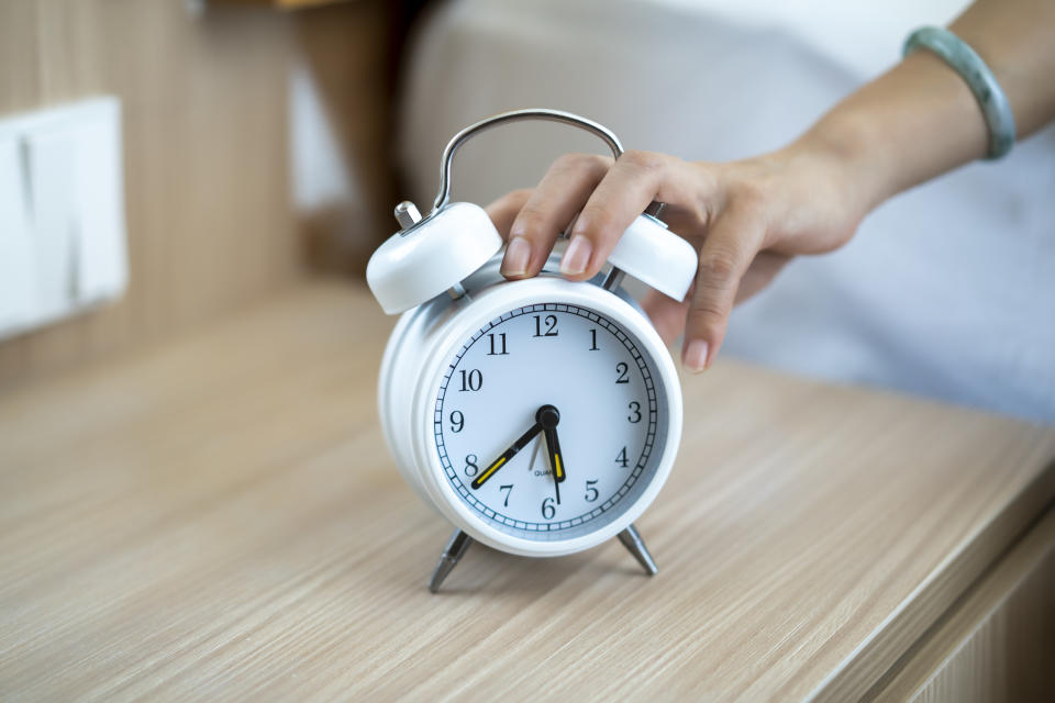 A woman's hand presses an alarm clock