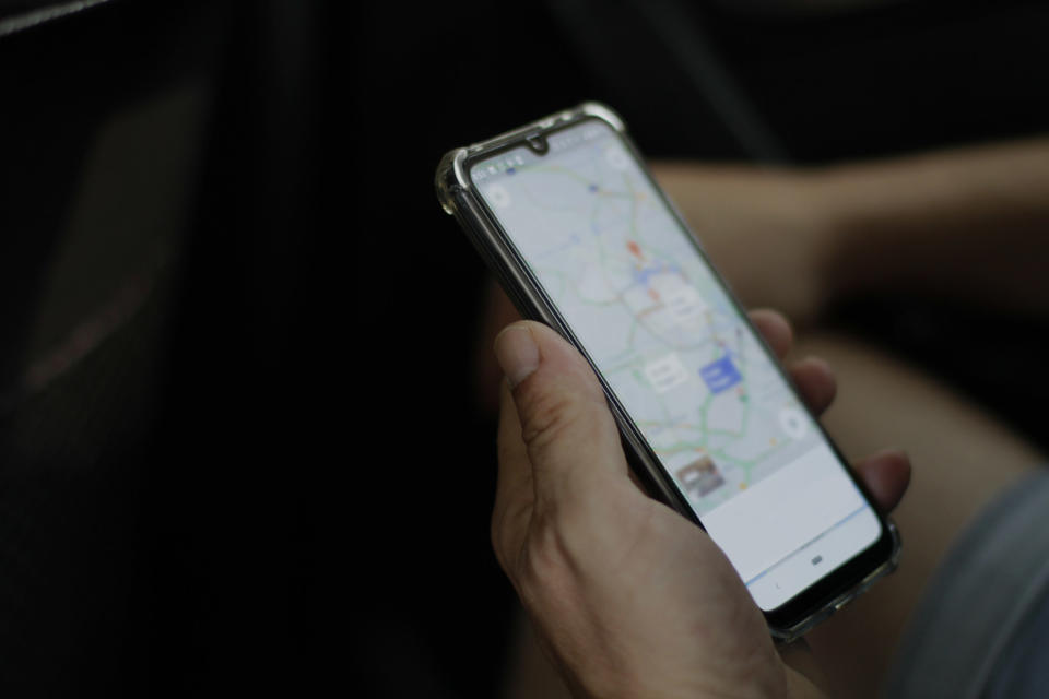 A hand holding a smartphone with a map on the screen.