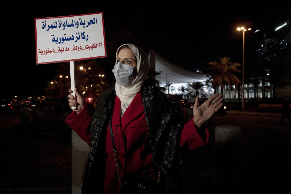 Mashael al-Shuwaihan, who sits on the board of Kuwait's Women's Cultural Society, speaks during an interview, at a protest outside Kuwait's National Assembly, in Kuwait City, Monday, Feb. 7, 2022. Her placard reads: "Freedom and equality for women are constitutional pillars." Women might be progressing across the Arab world, but in Kuwait, the guardians of conservative morals have increasingly cracked down on their rights in recent months, prompting activists to take to the streets last week. (AP Photo/Maya Alleruzzo)