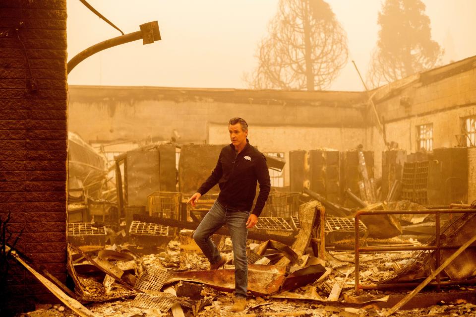 California Gov. Gavin Newsom walks over debris at the Greenville Post Office, which was destroyed by the Dixie Fire, on Saturday, Aug. 7, 2021, in Plumas County, Calif.