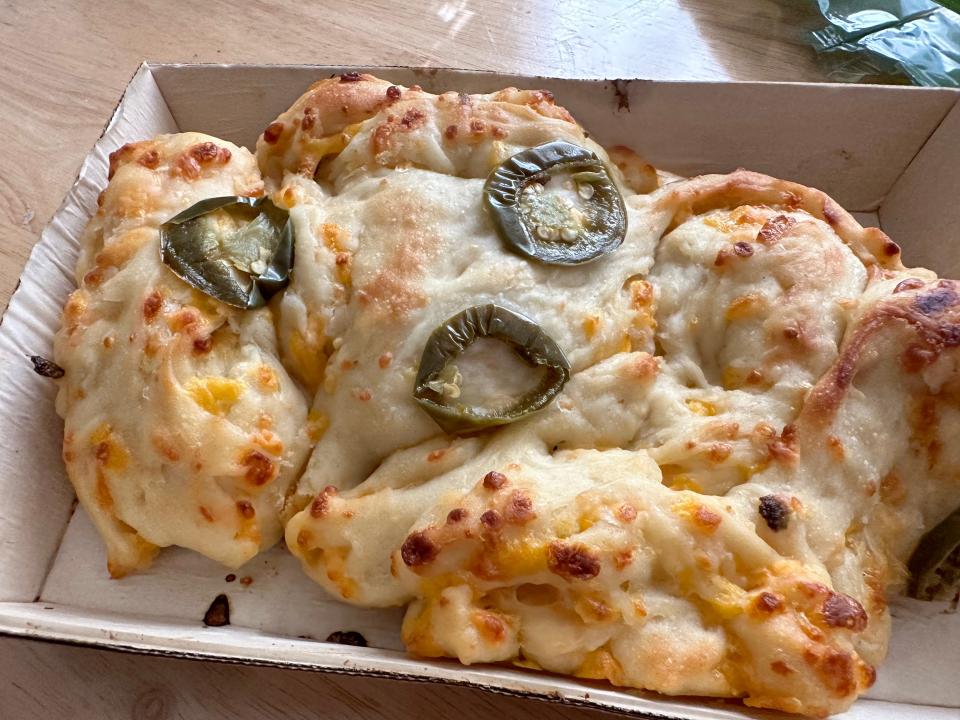 cheesy bread with three jalapeno rings on top of it all in a cardboard box