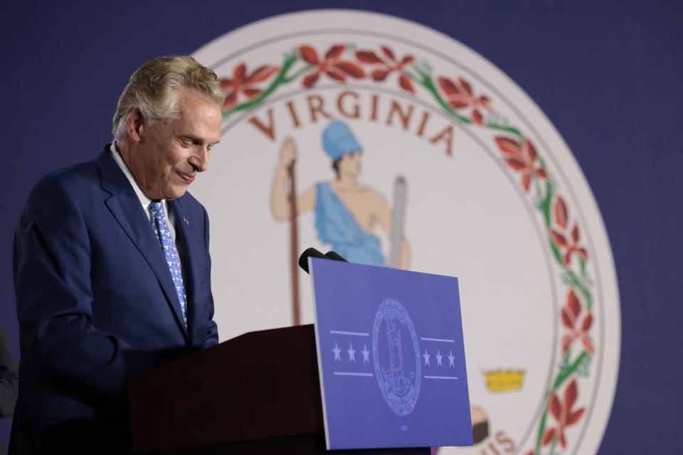 Terry McAuliffe, the Democratic gubernatorial candidate, speaks at a podium in front of the state shield.