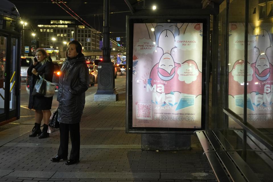 A woman stands near a banner that says: "A prospective mother thinks: 'What do I do now? Will I be able to handle it? Where to find support?'" at a bus stop in St. Petersburg, Russia, Monday, Oct. 23, 2023. Over three decades, Russia went from having some of the world's least-restrictive abortion laws to being what officials call a bulwark of “traditional values,” with the health minister condemning women for prioritizing careers over childbearing. (AP Photo)