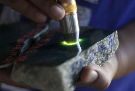 A buyer checks a jade stone near a mine dump at a Hpakant jade mine in Kachin state, Myanmar November 29, 2015. REUTERS/Soe Zeya Tun