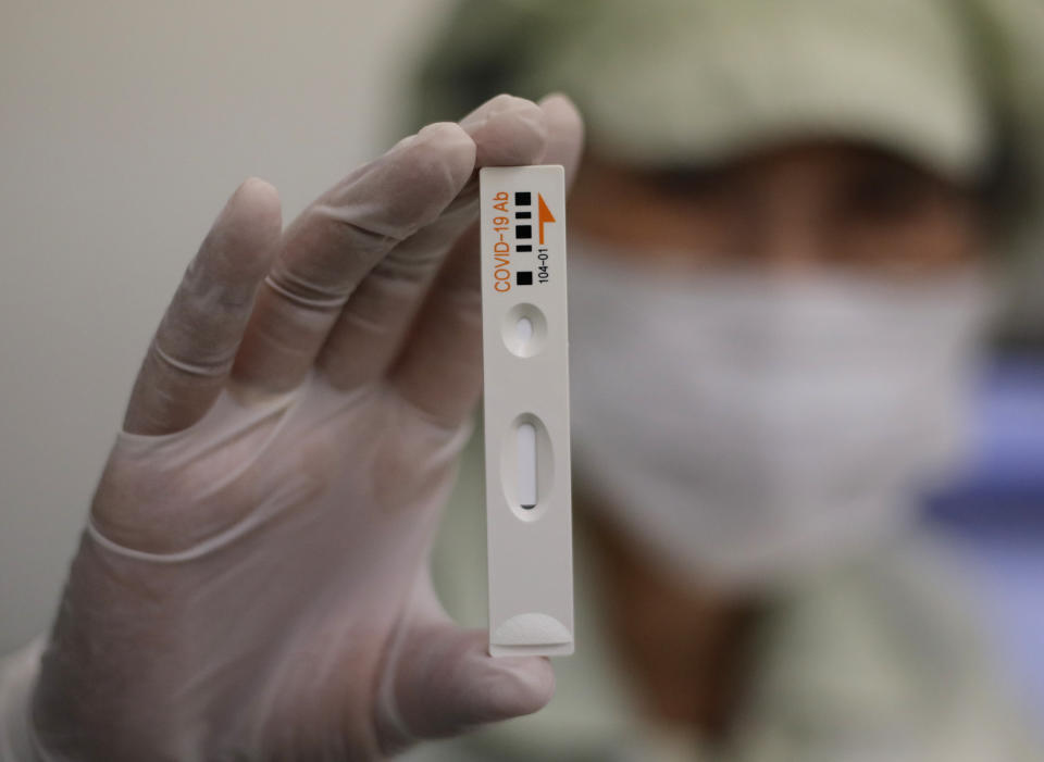 An employee holds up an antibody test cartridge of the ichroma COVID-19 Ab testing kit used in diagnosing the coronavirus in Chuncheon, South Korea, Friday, April 17, 2020. (AP Photo/Lee Jin-man)