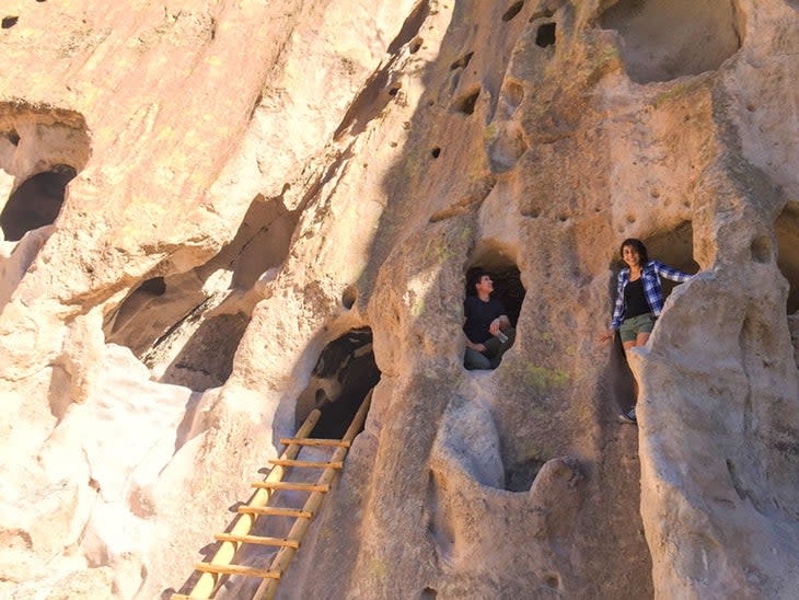 A couple explores cavates (carved rooms) at Bandelier National Monument