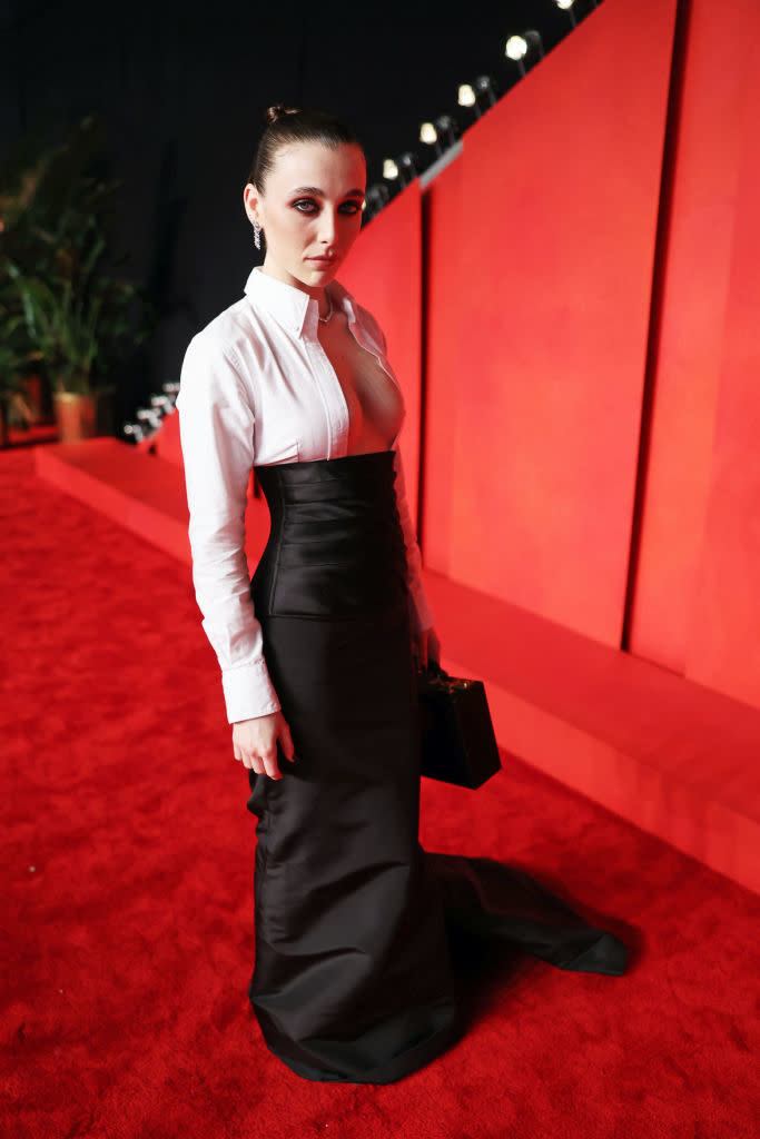 Woman in a white top and black skirt on the red carpet, poised stance, looking at camera
