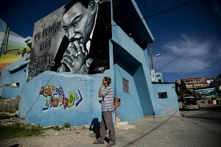 A tourist stands in front of a Martin Luther King graffiti in the Cova da Moura neighborhood of Amadora, on the outskirts of Lisbon, on October 23, 2014