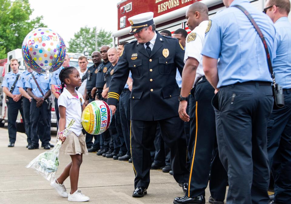 Dynasti Hartman walks hand in hand with Assistant Fire Chief Sam Castanza as members of the Montgomery Fire Department honor Forest Avenue Academic Magnet School student Hartman, daughter of injured firefighter Deandre Hartman in Montgomery, Ala, on Monday May 22, 2023. Deandre Hartman was injured in a fire on May 14th and is being treated in the UAB Hospital Burn abd Trauma ICU.