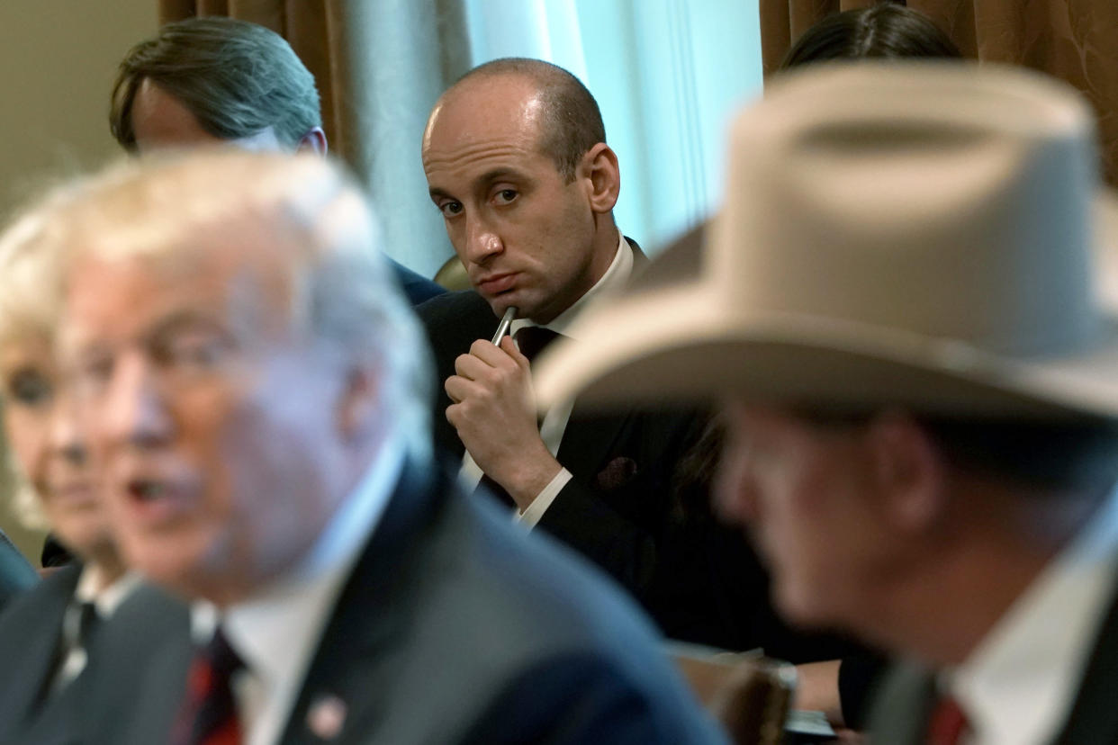 Trump sits with a few people as Stephen Miller, the only face in the frame that's in focus, listens from behind him with a pen to his chin.